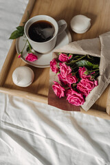 .Bouquet  of spring flowers and a cup of coffee on a wooden tray in bed. The concept of  valentine's day and women's day.Flat lay, top view with copy space.
