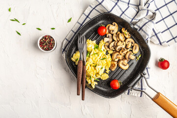 Scrambled Eggs with champignon mushrooms on frying pan for healthy breakfast or brunch, top view,...