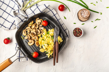 Scrambled Eggs with champignon mushrooms on frying pan for healthy breakfast or brunch, top view, copy space. Homemade meal recipe scrambled eggs