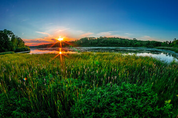 Sunset on the horizon with a fisheye lens for a wide view over a lake.