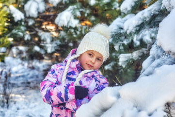 Portrait of a happy little girl on a winter walk . A child in comfortable clothes in the forest