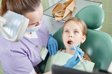 Child to the dentist. Child in the dental chair dental treatment during surgery. Small kid patient visiting specialist in dental clinic.