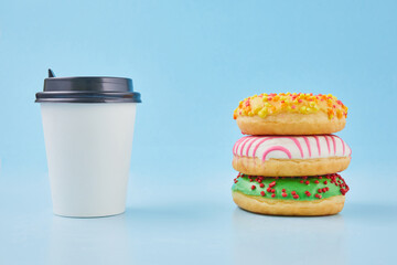 Sweet donut or doughnut with hot cup of fresh brewed coffee or tea. Takeaway paper cup with donuts. Breakfast at the coffee shop concept.