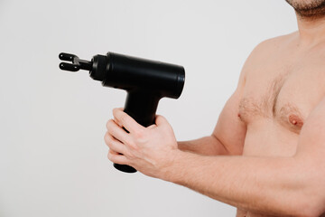 man holds massage gun. medical-sports device helps to reduce muscle pain after training, helps to relieve fatigue, affects problem areas of body, improves condition of skin.