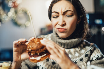 A frustrated woman frowns because she can't feel the aroma and taste of a hamburger, which is an...