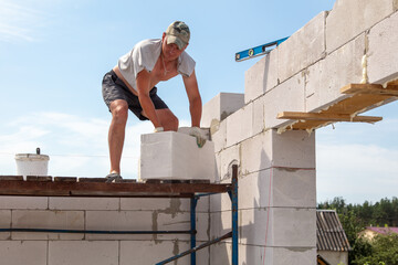 A worker builds the walls of a house from aerated concrete bricks.