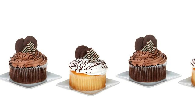 HD video above panning across row of cupcakes, alternating chocolate with vanilla on a white surface and background.
