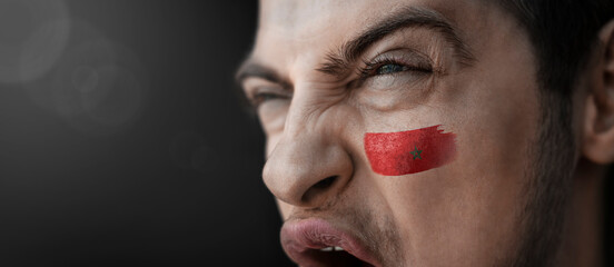 A screaming man with the image of the Morocco national flag on his face
