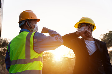 Asian industry construction site worker and foreman wearing hygiene face mask elbow bump greeting...