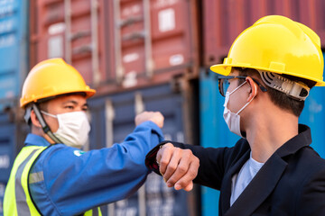 Asian industry construction site worker and foreman wearing hygiene face mask elbow bump greeting adaptation to prevent Coronavirus or Covid-19 spreading at warehouse, New Normal