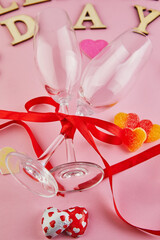 Valentine's day greeting card with glasses of champagne and candy hearts on pink background. Top view with the inscription Valentines day and a place for your greetings