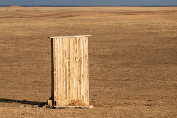 Photograph of an old rural outhouse or toilet in steppe. Single wooden building