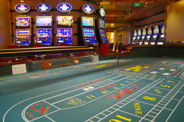 Teil von Spieltisch in Kasino auf Kreuzfahrtschiff mit Slotmaschinen im Hintergrund Glücksspiel -...