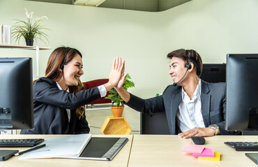 Business men and woman with headset as call center or business telesales on desk at the customer service office giving high five to be pleased with the success
