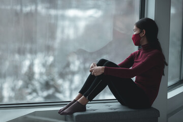 Winter depression because of coronavirus confinement. Sad Asian woman alone during city lockdown...