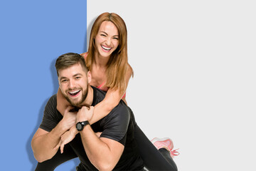 Portrait of cheerful fit sporty couple having fun on a split background of blue and light gray