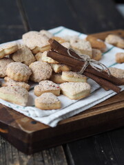 Homemade shortbread cookies sprinkled with sugar with cinnamon sticks on a kitchen board on a wooden background. Confectionery background.