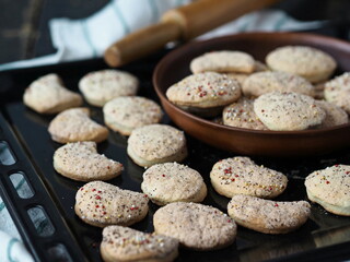 Homemade shortbread cookies sprinkled with sugar in a clay plate on a baking sheet on a dark wooden table.Confectionery background.