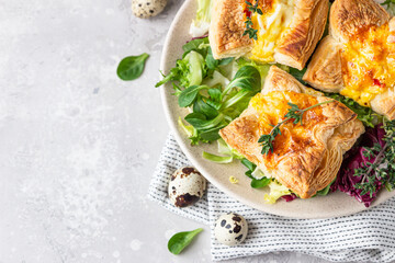 Puff pastry mini quiche, pie or tart with vegetables served on a plate with green mix salad. Top view.