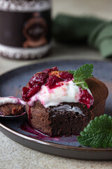 Mini chocolate cake or brownie with cream, cherry and mint on a ceramic plate. Chocolate fondant.