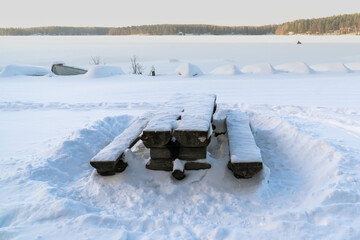 Snowy bench at a frozen Finnish lake
