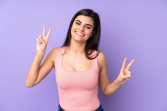 Young woman over isolated purple background showing victory sign with both hands