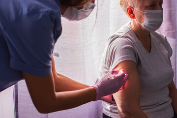 A girl doctor in pink gloves does a vaccination, a vaccine against coronavirus, flu, infections....