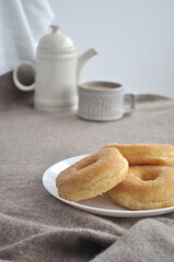 Fototapeta na wymiar Scandinavian coffee break. Still life with a kettle, a cup of coffee with milk and donut. Dessert, baking photo. Minimalistic and concise photo of food in neutral light and beige tones