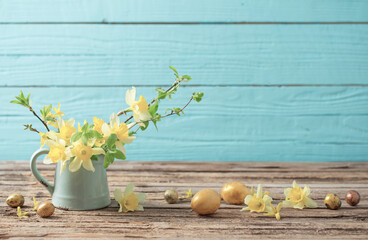 Golden Easter eggs and yellow flowers on wooden background