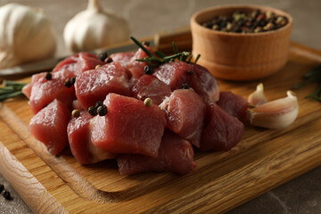 Board with raw meat, herbs and spices on gray background