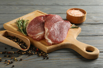 Board with raw steak meat, herbs and spices on wooden background