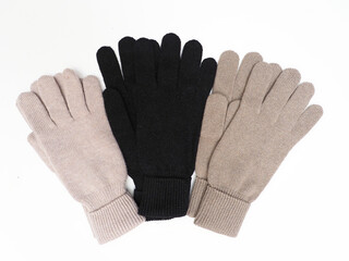 Warm woolen gloves of different colors on a white background.