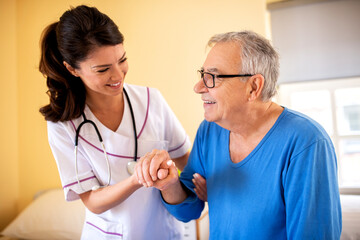 Female doctor in a nursing home facility holding her patient for hand