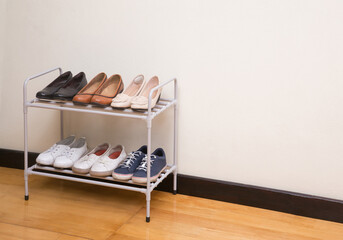 Small metal shoe shelf with women shoes on wooden floor