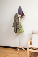 Wooden coat rack with jacket, hats and handbag in the room