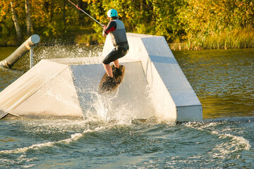 Wakeboarder making tricks. Low angle shot of man wakeboarding on a lake. Man water skiing at sunset.