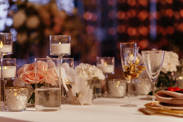 Obraz na płótnie Canvas Decorated table setting background. Glasses, candles in the candlesticks, and roses. Banquet