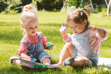 Two little girls sisters paint with finger paints