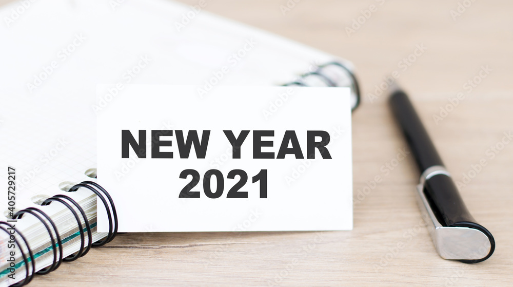 Poster card with text 2021 new year on the table next to a notebook and pen. business and finance