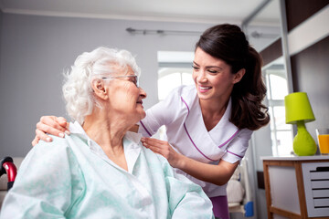 Ladies having a friendly conversation, diligent nurse and senior resident patient