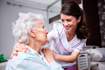 Ladies having a friendly conversation, diligent nurse and senior resident patient