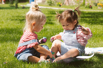 Two little girls sisters paint with finger paints