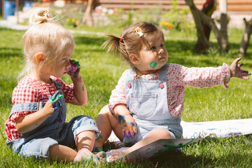 Two little girls sisters paint with finger paints