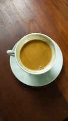 Milk coffee in a white cup against a wooden table background