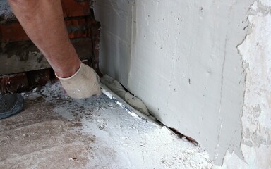 the hand of the plasterer applies a layer of wet mortar of the finishing putty, leveling the wall, wide trowel in the work of the builder with gypsum plaster, building background with copy space