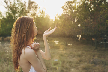 attractive woman in a white sundress resting in nature at sunset