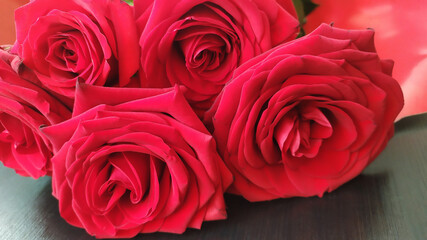 a bouquet of five scarlet roses lies on the floor close-up
