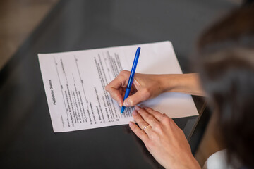 Woman signing a petition for divorce with a pen