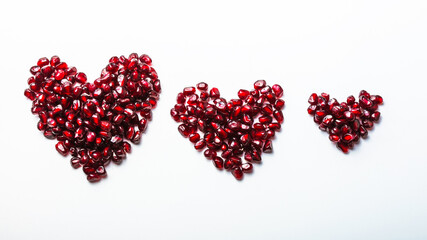 Hearts shape pomegranate seeds on white background.  Valentines helthy love concept.