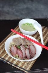 a bowl of noodle with pork meat and soup